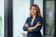 © amnaj - Pretty and confident young Asian business woman standing with her arms crossed and smiling brightly at the camera in the office.
