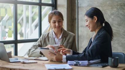 Wall Mural - Two young Asian businesswoman consult and talk analysis of marketing planning and office budgeting.