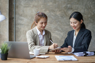 Wall Mural - Two young Asian businesswoman consult and talk analysis of marketing planning and office budgeting.