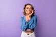 © Look! - Cute young blonde caucasian woman smiles teeth at camera on purple background. Model with wavy hair is wearing blouse. Lifestyle, female beauty concept