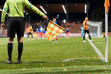 Wall Mural - Soccer touchline referee with the flag shows corner during match at the football stadium.