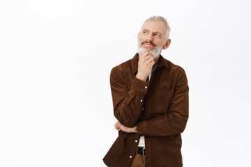 Thoughtful senior man, looking aside and planning, thinking of something, standing against white background in casual clothes