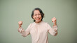© bongkarn - Happy 60s senior Asian woman raising hands, showing strong arms and healthy body