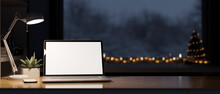 Cozy Workspace In Christmas Night Theme, Laptop White Screen Mockup, Table Lamp On Table