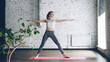 Young slim blond girl is doing yoga complex in nice studio with white walls. She is starting with warrior poses, then bending forward and backward and finishing with namaste.