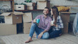 © silverkblack - Girlfriend and boyfriend are talking making plans sitting on floor of new purchased apartment, looking around and holding mugs. Relationship, people and relocation concept.