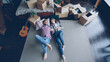 © silverkblack - Top view of loving young couple lying on bedroom floor in new apartment and talking. Guitar, packed things in carton boxes, double bed and modern carpet are visible.
