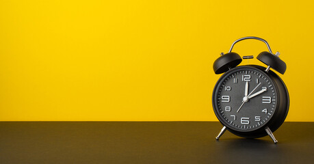 Wall Mural - Black friday sales concept. Photo of black alarm clock on desktop yellow wall background with empty space