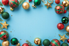 Christmas Day Concept. Top View Photo Of Red Green And Gold Baubles Star Ornaments Pine Branches And Shiny Confetti On Isolated Light Blue Background With Copyspace In The Middle