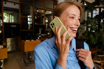 Wall Mural - Young white woman wearing shirt smiling while talking on cellphone