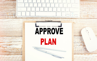 APPROVE PLAN text on a clipboard with keyboard on wooden background