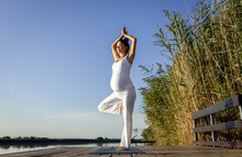 Pregnant Woman Doing Yoga At Lake During The Day.