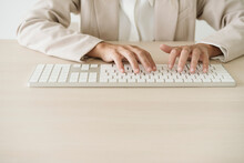 Close-up Of Businesswoman Typing On Keyboard At Desk