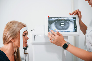 Side view. Woman's vision is tested by clinic worker that using special device