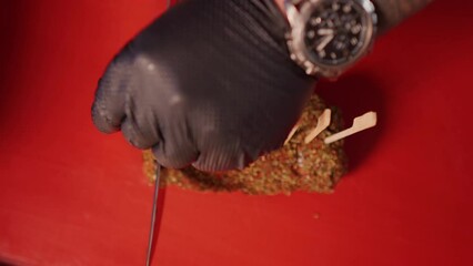 Wall Mural - Top view of cook slicing a rolled beef seasoned with spices. Chef prepared beef cuts for barbecue.