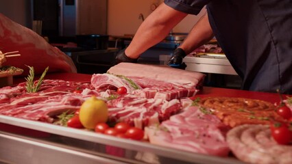 Wall Mural - Butchers shop man hands removing the fat from raw pork meat. Degreased hunk of raw pork. Concept of bio products.