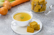Homemade vegetable cubes with ready to eat bouillon in a bowl and ingredients on background.