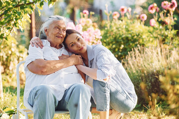 Time for a hugs. Young woman is with her senior mother is in the garden