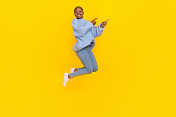 Wall Mural - Full size photo of young girl jump air directing fingers empty space attention new clothes shop sales isolated on yellow color background