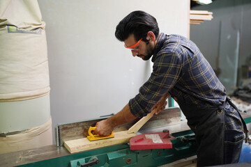 Contemporary Carpenter Working, Portrait of modern carpenter making wood furniture while working in joinery lit by sunlight with factory background on small business concept, copy space