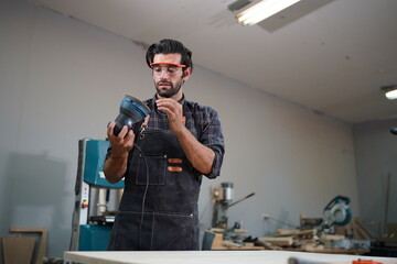 Contemporary Carpenter Working, Portrait of modern carpenter making wood furniture while working in joinery lit by sunlight with factory background on small business concept, copy space