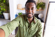 © WavebreakMediaMicro - Happy african american man sitting at table in kitchen, having video call