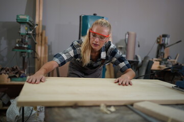 Contemporary Carpenter Working, Portrait of modern carpenter making wood furniture while working in joinery lit by sunlight with factory background on small business concept, copy space