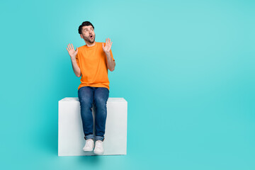 Sticker - Full length photo of guy impressed empty space poster banner sit white cube isolated on cyan color background