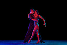 Stylish Ballroom Dancers Couple In Gorgeous Outfits Dancing In Sensual Pose On Dark Background In Neon Light. Concept Of Art, Music, Dance, Emotions.