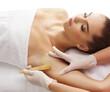 © Acronym - Hair removal, beauty and health concept. A young girl is getting an epilation procedure. A processional beauty worker is making depilation with hot wax.