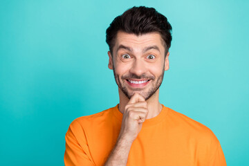 Wall Mural - Closeup photo of young handsome pretty nice guy wear orange t-shirt touch bearded chin toothy smile excited positive empty space offer isolated on cyan color background