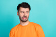 Photo of young handsome funny grimace attractive student guy wear orange t-shirt tongue unhappy grimace look empty space isolated on cyan color background