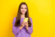 © deagreez - Photo of young pretty girlish lady wear violet pullover smiling good mood hold her smartphone watching tiktok video isolated on yellow color background