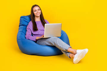 Wall Mural - Full length photo of pretty positive lady sit comfort bean bag use netbook home education empty space isolated on yellow color background