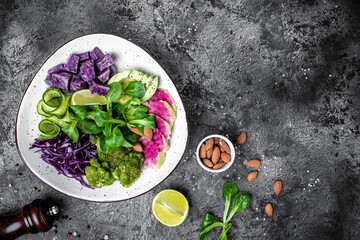 Wall Mural - salad with sweet potatoes, broccoli, avocado, purple cabbage, cucumber, watermelon radish and almonds on a dark background. place for text, top view