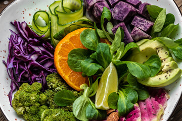 Wall Mural - Green salad with sweet potatoes, broccoli, avocado, purple cabbage, cucumber, watermelon radish and almonds. Food recipe background. Close up