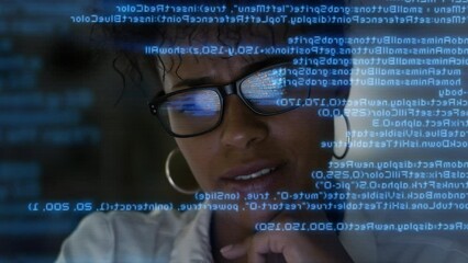 
Lateral Dolly Focused Young African American Software Developer or Engineer  Working on Computer, Line of Program Code Projected on His Face and Reflecting. Augmented Reality Machine Learning Data Al
