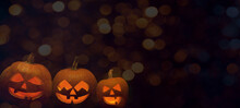 Scary Halloween Celebration Party Holiday Card Banner Panorama - Many Spooky Carved Glowing Pumpkins Jack O Lantern With Orange Bokeh Lights In The Dark Night