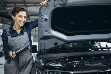 Young woman car mechanic checking car at car service