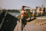 Active young beautiful woman running on the promenade along the riverside
