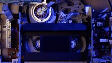 Old Video Recorder Inside Close-up, VHS. Retro Player In Neon Blue Light, Vintage Video Cassette Broadcasting, Audio Tape. 