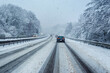 Autos auf deutscher Autobahn mit Schneematsch und Schneefall im Winter