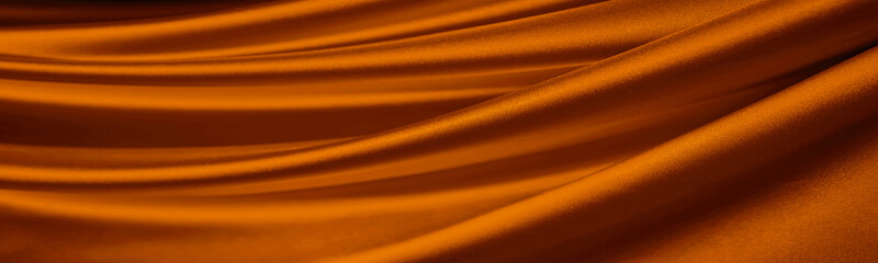 Dark orange brown silk satin. Drapery fabric. Curtain. Luxury background for design. Beautiful soft folds. Wavy lines. Golden color. Web banner. Wide. Long. Panoramic. Website header.