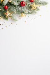 new year concept. top view vertical photo of pine branch in snow decorated with red baubles gold sta