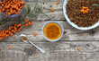 Sea buckthorn tea. Twig, fresh and dried sea buckthorn berries and cup of hot drink on wooden background. Top view. Pressed dried sea buckthorn berries in bowl. 
