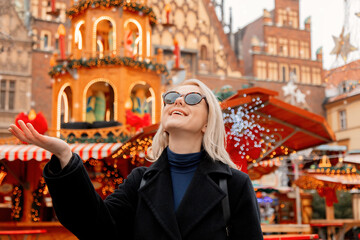 blond hair woman in sunglasses near christmas fair decorations in wroclaw, poland. 2021