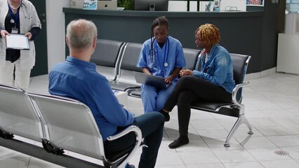 Wall Mural - Medical assistant showing disease diagnosis on laptop to young patient sitting in hospital reception waiting area. Female nurse consulting woman at checkup visit appointment, healthcare.