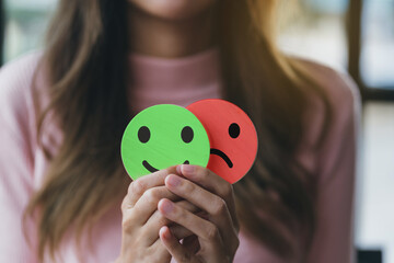 woman hands holding sad face hiding or behind happy smiley face, bipolar and depression, mental heal