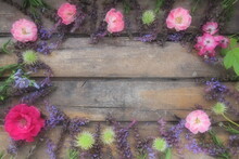 Flowers In A Circle On A Wooden Background. Postcard For The Holiday. Roses, Geraniums, Lavender, Sage And Hairy Chestnuts Are Placed Along The Edges On Dark Boards. Background Copy Space, Flat Lay.