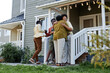 © Seventyfour - Full length portrait of happy black family embracing on porch of new house, copy space